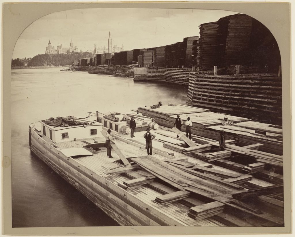 Chargement du bois au quai Booth et les anciens édifices du Parlement d'Ottawa au loin
